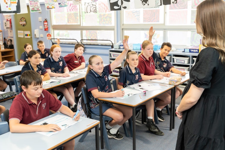 Picture of students raising hands asking teacher a question