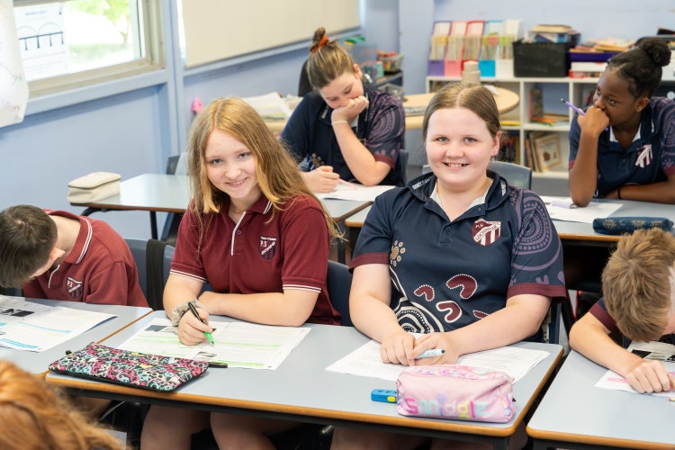 picture of 2 students learning and writing in books in classroom