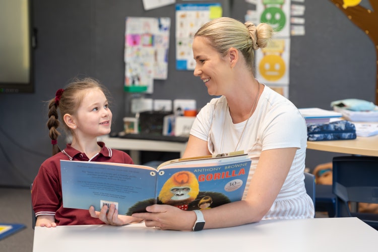 Teacher reading book with student