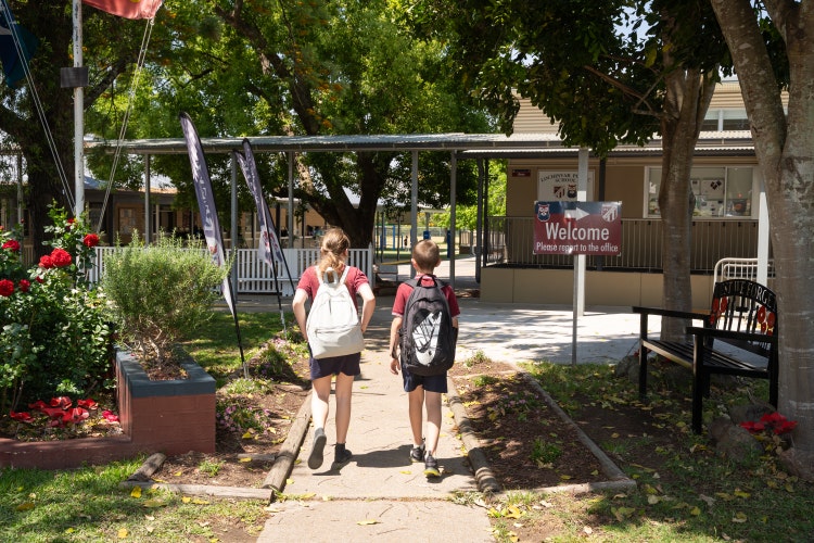 Picture of 2 students walking on school gate with bags on their backs